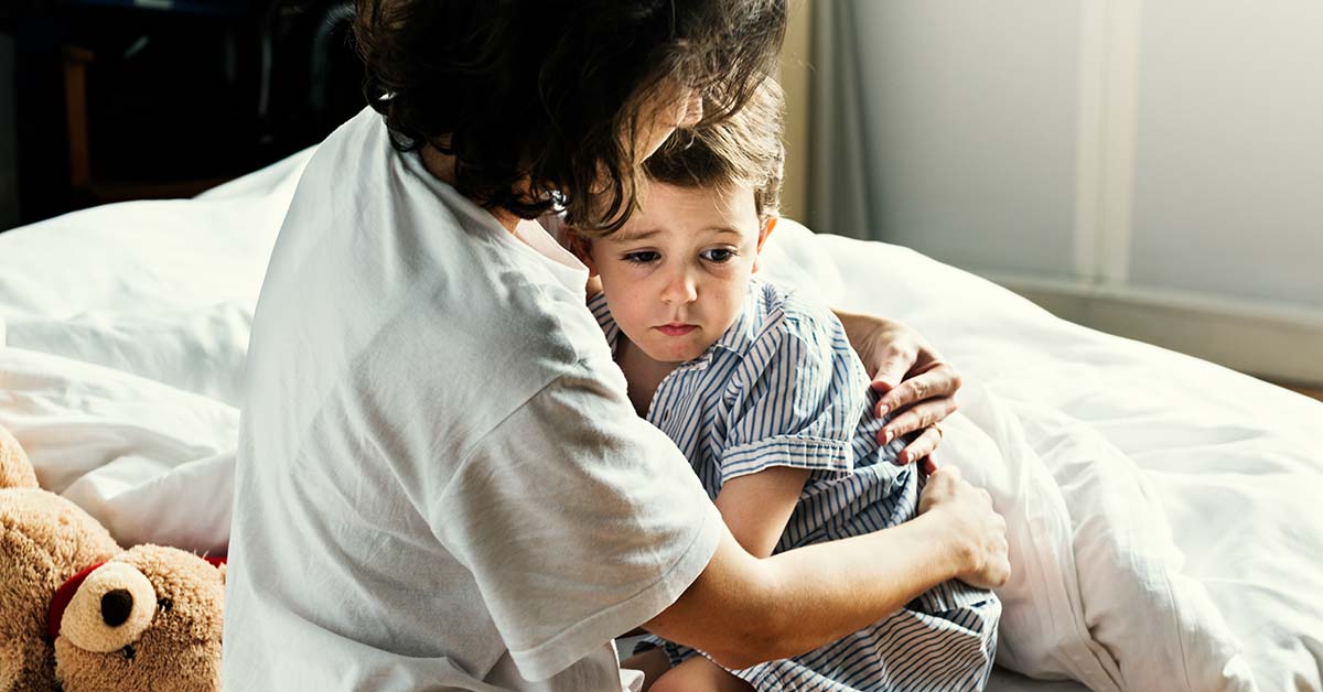 mãe abraçando criança com medo na cama